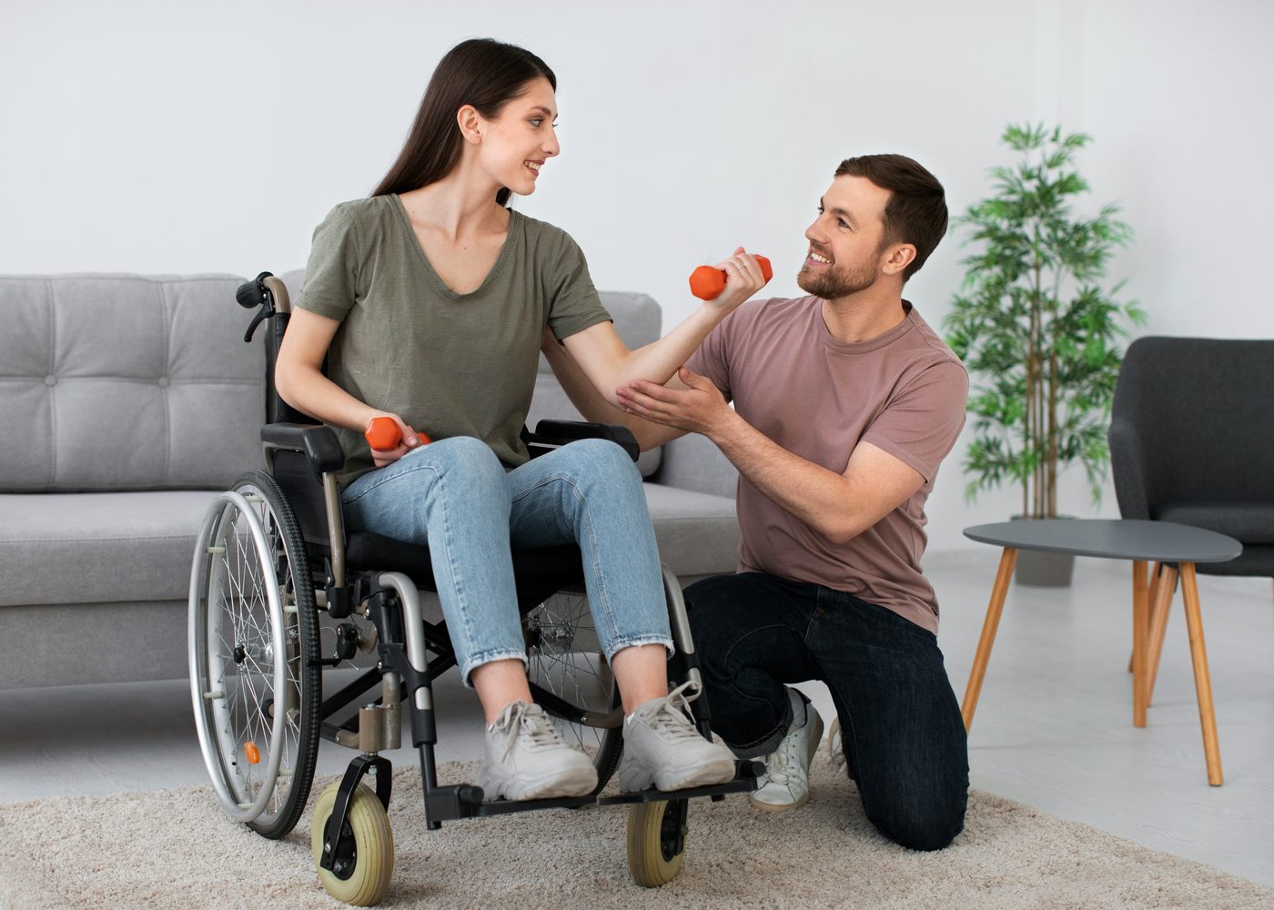 A physiotherapist guiding a client through a seated resistance exercise during a home visit